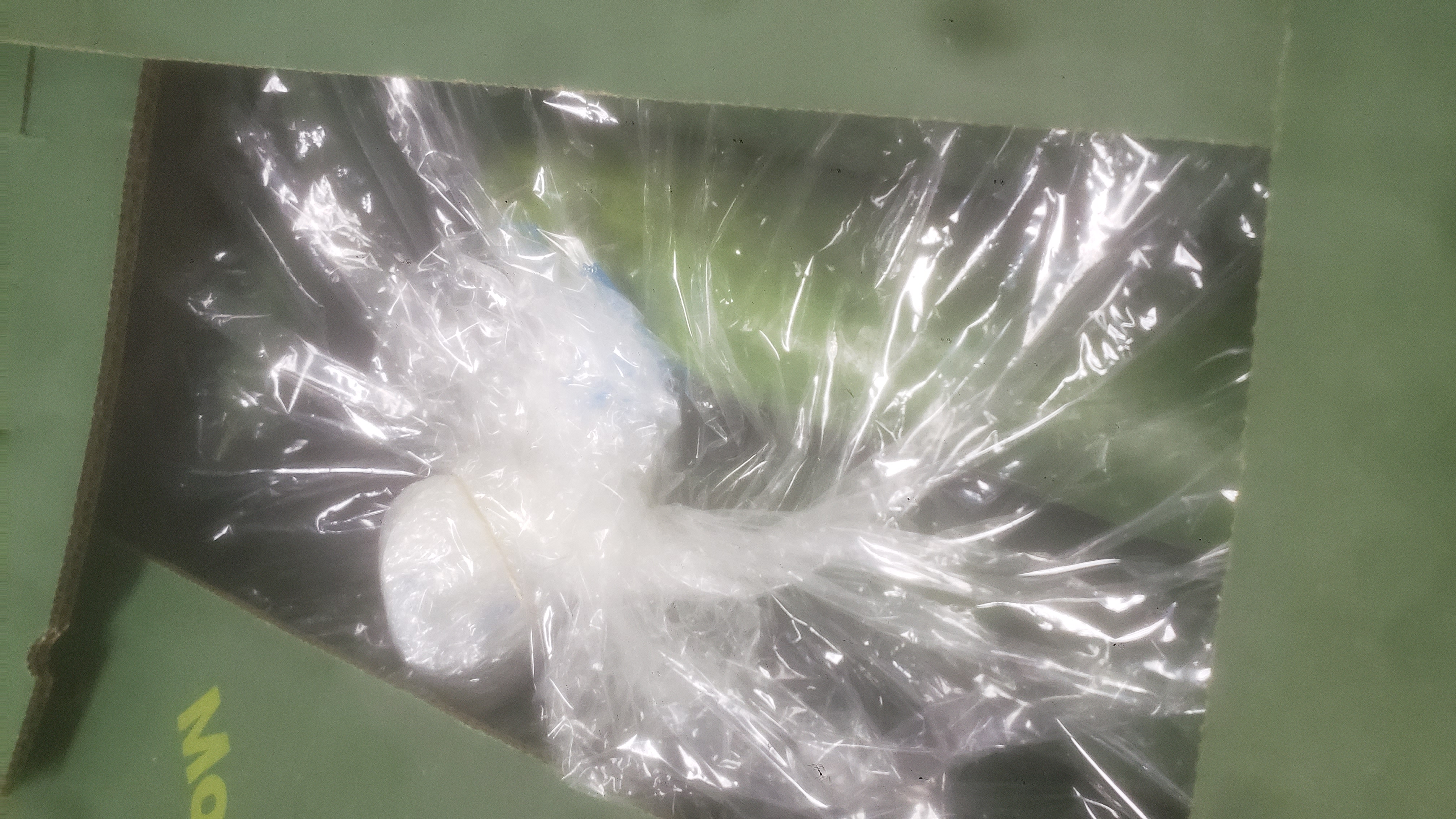 Cucumbers covered in plastic peeking out of a cardboard box.